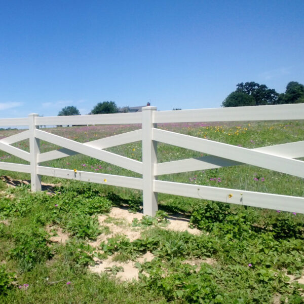 Crossbuck white vinyl horse fence around wildflower field