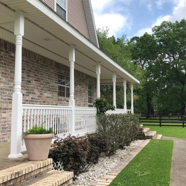 Ashington white vinyl railing on porch with shrubbery