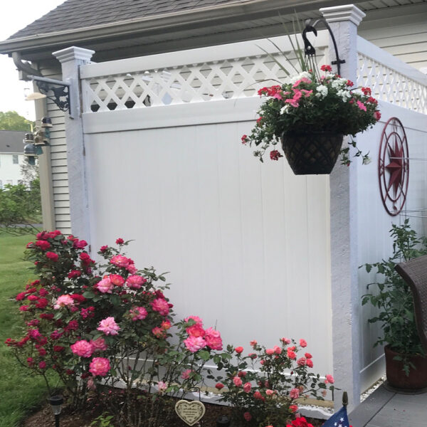 Canterbury white vinyl privacy fence and gate behind pink flowers