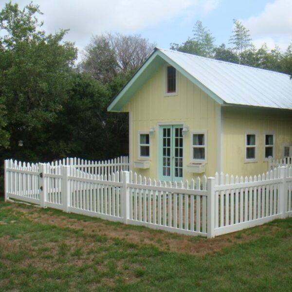 Grantham white vinyl picket fence around small yellow house
