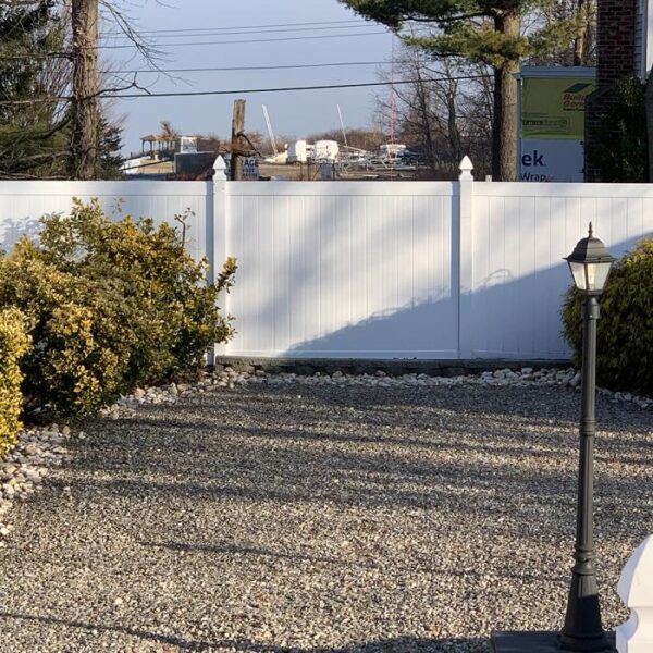 Wendell white vinyl privacy fence in gravel yard