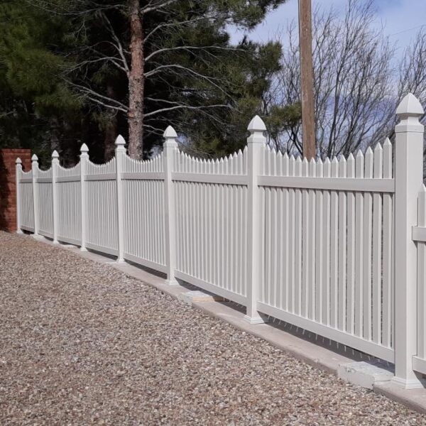 Rochdale white vinyl picket fence along gravel yard