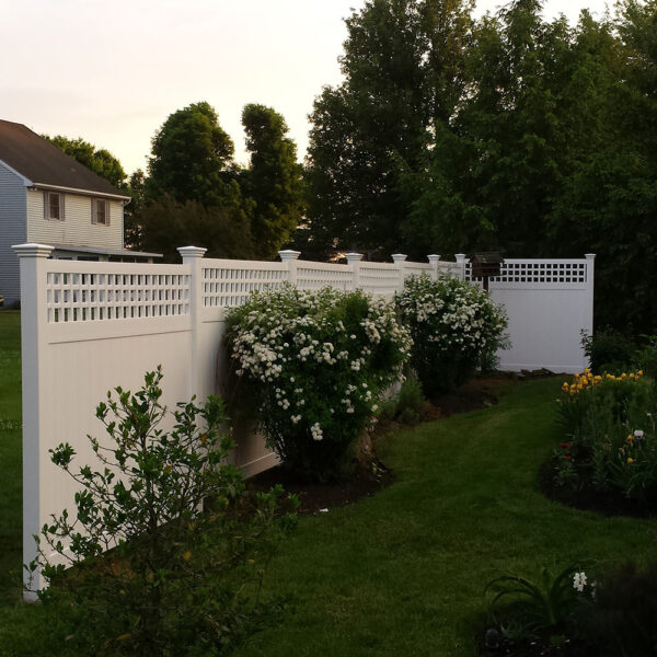 Cyrus white vinyl privacy fence stepped with flowering bushes